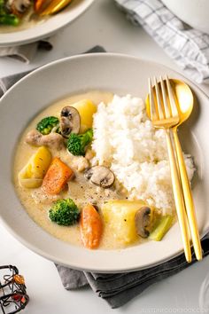 two plates with rice, broccoli and carrots on them next to silverware