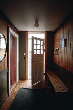 an empty room with wooden paneling and a bench in front of the door that leads to another room