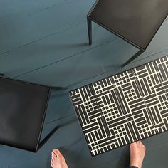 a person standing on the floor with their feet up in front of two black chairs