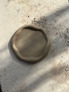 a gray plate sitting on top of a white floor next to a black object with one end missing