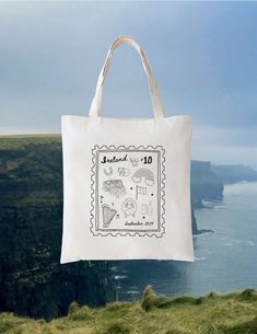 a tote bag hanging from the side of a cliff overlooking the ocean and cliffs