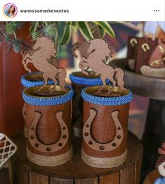 two brown and blue vases with horses on them sitting next to each other in front of a potted plant