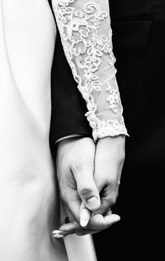 the bride and groom hold their hands together in black and white, while holding each other's hand