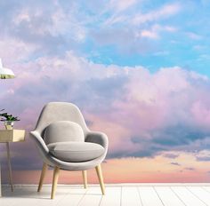 an empty chair and table in front of a cloudy sky wallpapered with clouds