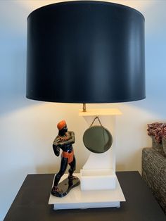 a lamp that is sitting on top of a table next to a mirror and figurine