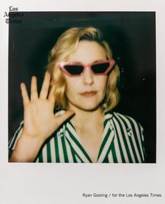 a woman wearing sunglasses and holding her hand up to the camera with both hands in front of her face