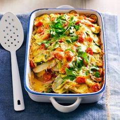 a casserole dish with tomatoes, zucchini and spinach