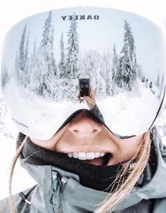 a woman taking a selfie in the snow with her ski goggles over her face