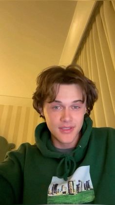 a young man wearing a green hoodie taking a selfie