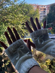 a person's hand wearing white knitted gloves