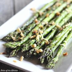 asparagus on a white plate topped with nuts