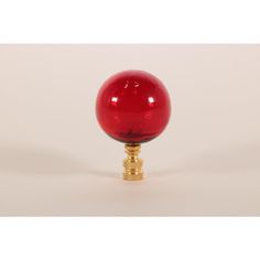 a red glass ball sitting on top of a golden base