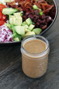 a salad in a bowl with dressing next to it