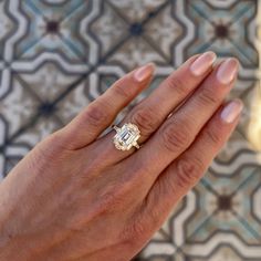 a woman's hand holding an engagement ring with a diamond in it on top of a tiled floor