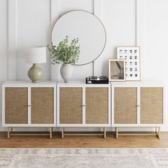 a white cabinet with wicker doors and a round mirror on top next to it