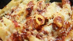 closeup of pasta with sauce and cheese in a black bowl on the stove top