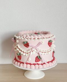 a pink cake decorated with strawberries and ribbons