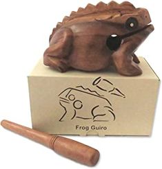 a frog figurine sitting on top of a cardboard box with a wooden handle