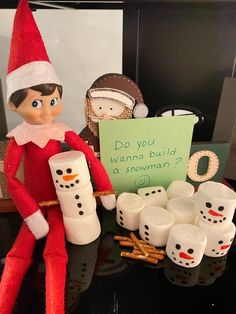 an elf is sitting next to some marshmallows and a sign that says do you wannan't build a snowman?