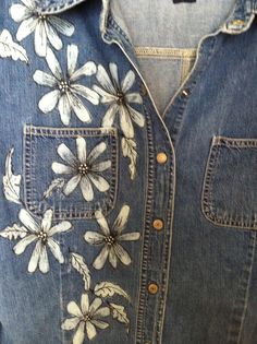 an embroidered denim shirt with flowers on the front and back pockets, worn by someone