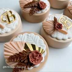 four decorated cookies sitting on top of a white table next to some brown and gold decorations