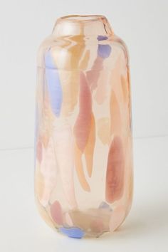 a glass vase sitting on top of a white table next to a blue and pink object