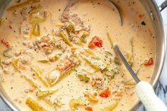 a pot filled with soup and vegetables on top of a table next to a spoon