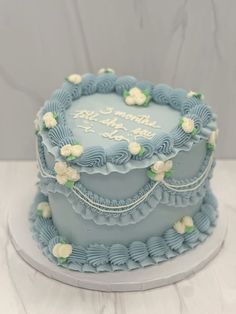 there is a blue cake with white flowers on the top and bottom, sitting on a plate