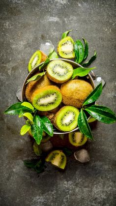 kiwis in a metal bowl with leaves and ice on the side, viewed from above