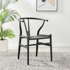 a black chair sitting on top of a rug in front of a potted plant