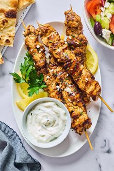 grilled chicken skewers with greek salad and pita bread on the side