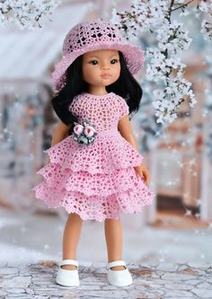 a doll wearing a pink crochet dress and hat with flowers in her hand