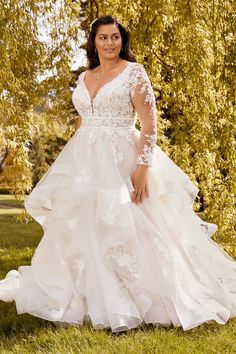 a woman in a wedding dress standing under a tree with her hands on her hips