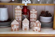 gingerbread houses are displayed on a shelf with plates and dishes in the background,