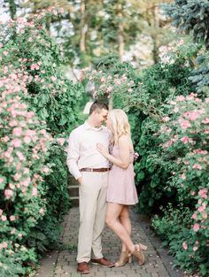 an engaged couple standing in front of pink flowers