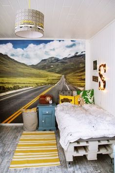 a room with a bed, rug and wallpaper on the walls that has a road painted on it