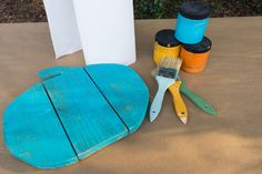 some paint brushes are sitting on top of a surfboard and other items for painting