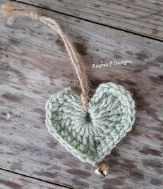 a crocheted heart ornament hanging from a string on a wooden surface