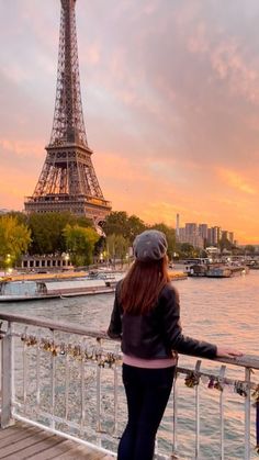 a woman standing on a bridge looking at the eiffel tower