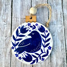 a ceramic ornament with a blue bird on it's side hanging from a rope