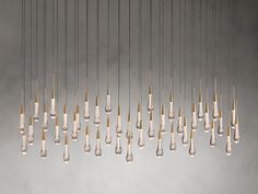 a bunch of lights that are hanging from the ceiling in front of a gray wall