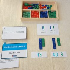 a wooden box filled with lots of colorful magnets next to cards and numbers on a table