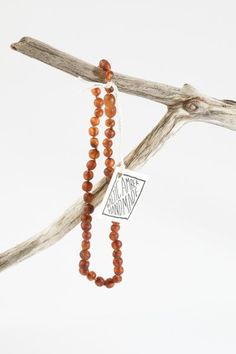 the beaded necklace is hanging on a branch with a tag that says, happy mother