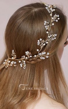 a woman with long hair wearing a gold headpiece and white flowers on it's side