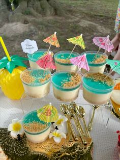 there are many desserts on the table with beach umbrellas and pineapples