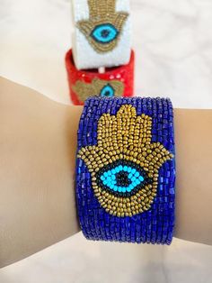 All the vibes you need to keep the evil away in one bracelet. A intricate Hamsa and a bold evil eye design crafted into a luxurious chic  bracelet.  Always protected!! Timeless enough to be worn with any outfit. Slides on and off with an open cuff flexible enough to fit everyone.Comes in sleek FRESHALAMODE packaging making it perfect for gifting. A hamsa prayer card is included as well. Choose between 3 rich colors. RedWhite Blue Symbolic Handmade Bracelets For Festivals, Spiritual Beaded Wristband Bangle, Bohemian Bangle Stretch Bracelet For Party, Bohemian Stretch Bangle Bracelet For Parties, Bohemian Evil Eye Bracelet With Colorful Beads, Handmade Symbolic Beaded Bangle Bracelets, Spiritual Beaded Cuff Bracelet Gift, Handmade Symbolic Beaded Bangle Bracelet, Bohemian Beaded Evil Eye Bangle Bracelet