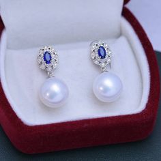 Make a lasting impression with the 11-12mm Freshwater Pearl & Blue Gem Cubic Zirconia Earrings-. These gorgeous earrings are set in a vintage-inspired silver alloy setting and feature shimmering white freshwater pearls and blue Cubic Zircoina gems. The combination of these two elements will bring a touch of elegance to any look, making them perfect for any occasion. Showcase your style and sophistication with this timeless piece from House of Pearls. This popular earrings design features AAAA qu Popular Earrings, Gem Earrings, Purple Earrings, Cubic Zirconia Earrings, White Freshwater Pearl, Blue Gems, Zirconia Earrings, Pearl Types, Pearl Color