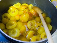 olives and lemons cooking in a pot with a wooden spoon on the side