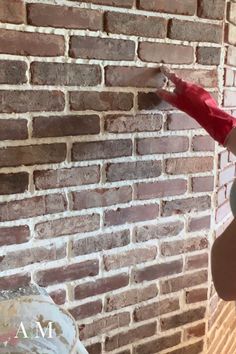 a person holding an umbrella in front of a brick wall