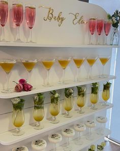 there are many glasses on the shelf with different drinks in them and one is empty